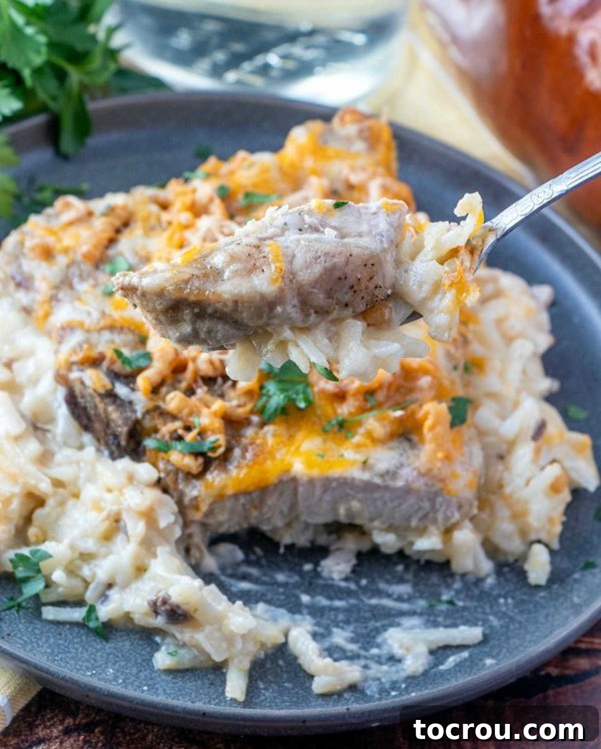 bite of cheesy pork chop and potatoes on fork, ready to eat. 