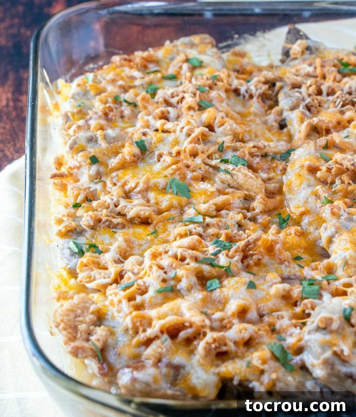 Casserole dish loaded with cheesy pork chop and potato bake topped with french fried onions and fresh herbs.