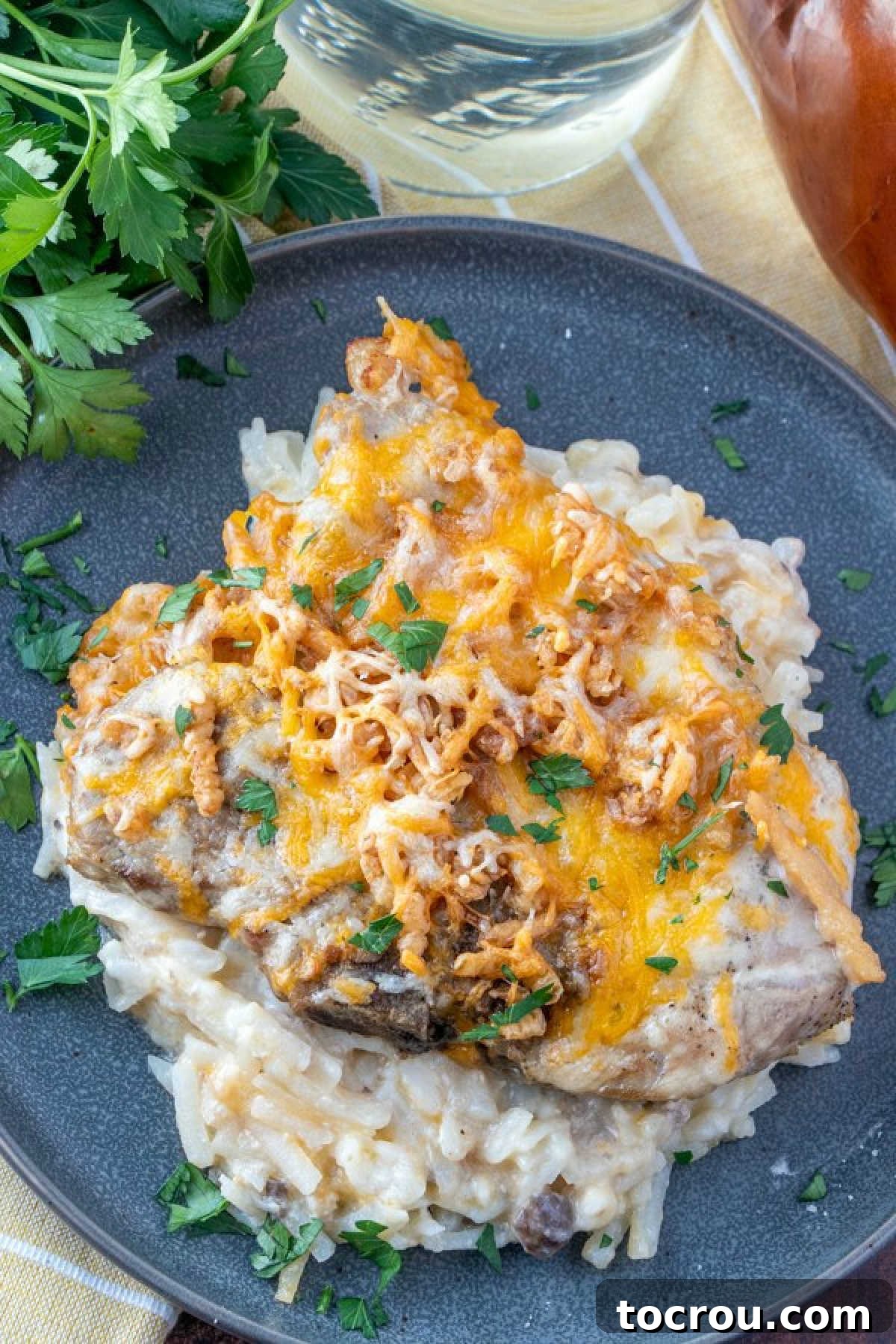 Cheesy pork chops and potatoes served on plate.