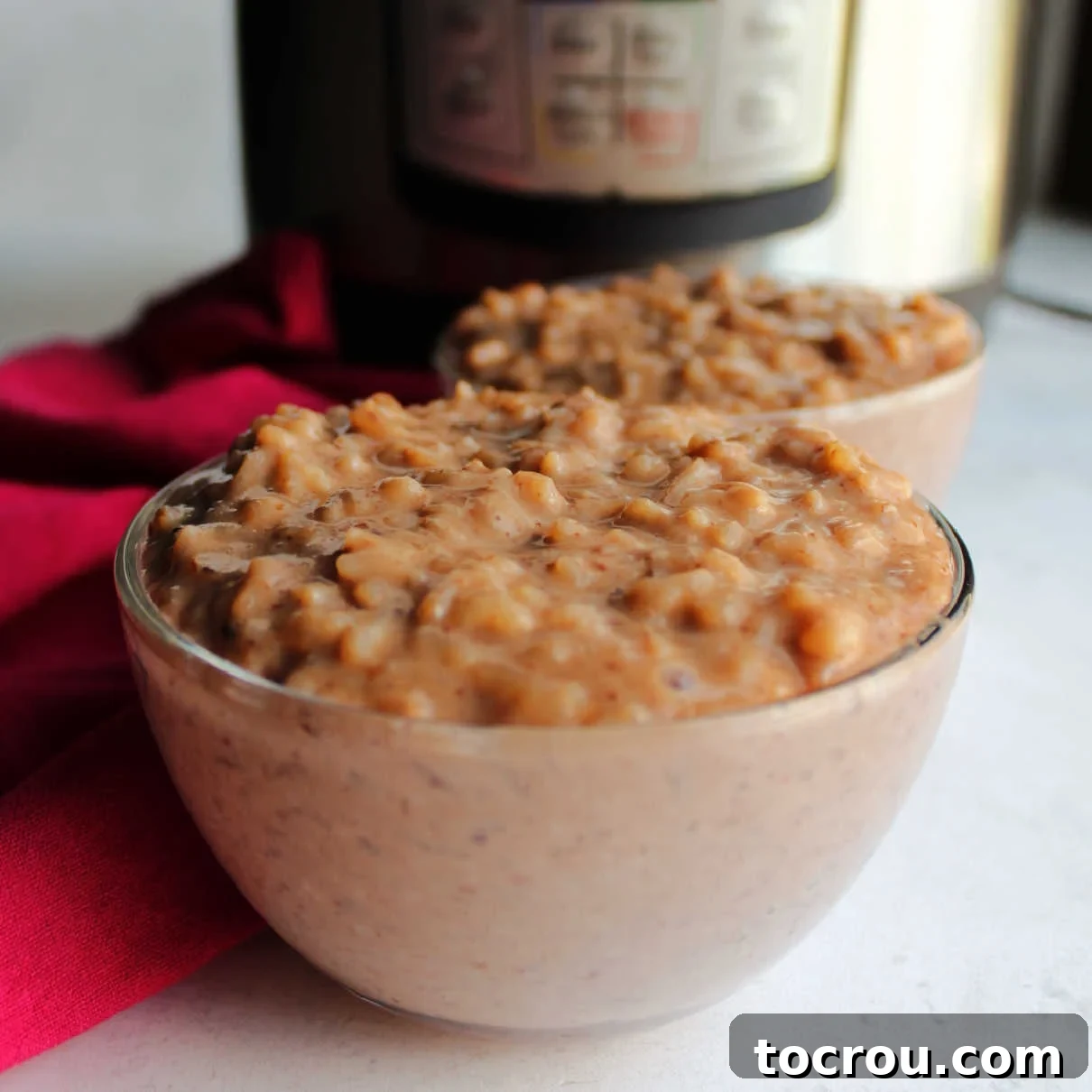 Decadent Instant Pot Chocolate Rice Pudding 2 Two small glass bowls filled with creamy chocolate rice pudding in front of pressure cooker.