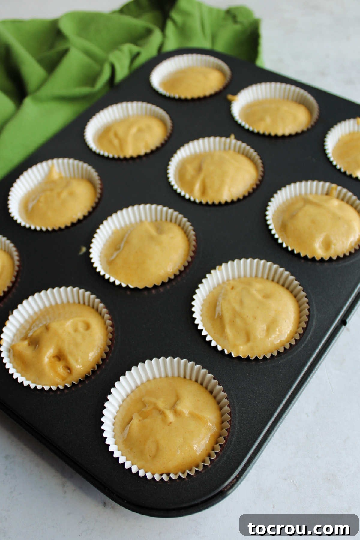 Apple butter cake batter scooped into paper lined mini cupcake tin.