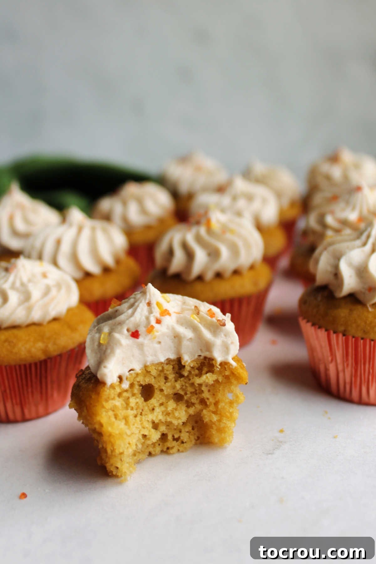 half of an apple butter mini cupcake showing moist apple butter cake and tan apple butter frosting.