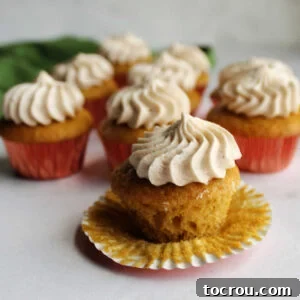 Apple butter mini cupcake unwrapped showing soft cake bottom topped with swirl of apple butter frosting.