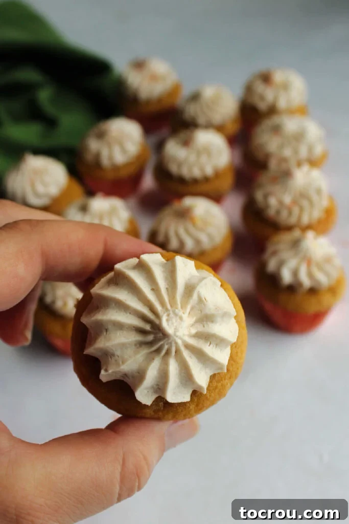 Hand holding a mini apple cupcake topped with a star shaped apple frosting.