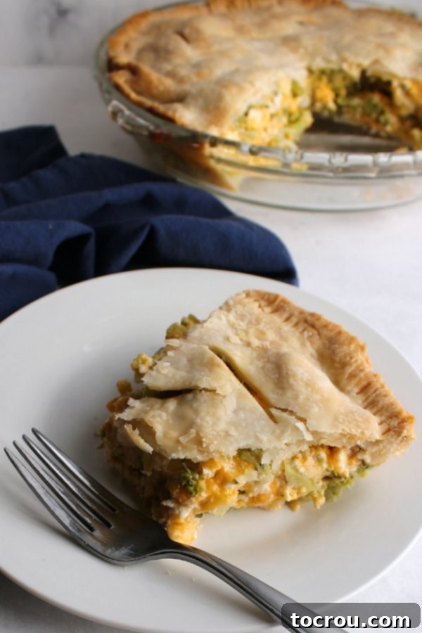 A slice of ham, broccoli, and cheese pot pie with a bite missing, showcasing the creamy filling and flaky crust.