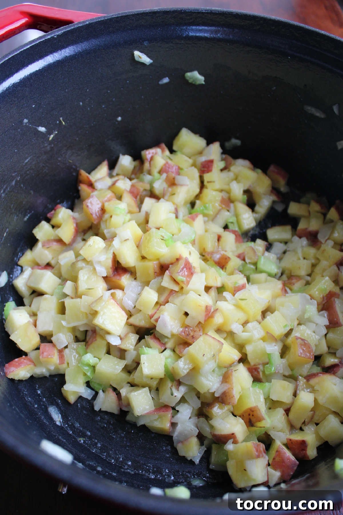 small cubes of potato, chopped celery and onion being cooked in dutch oven.