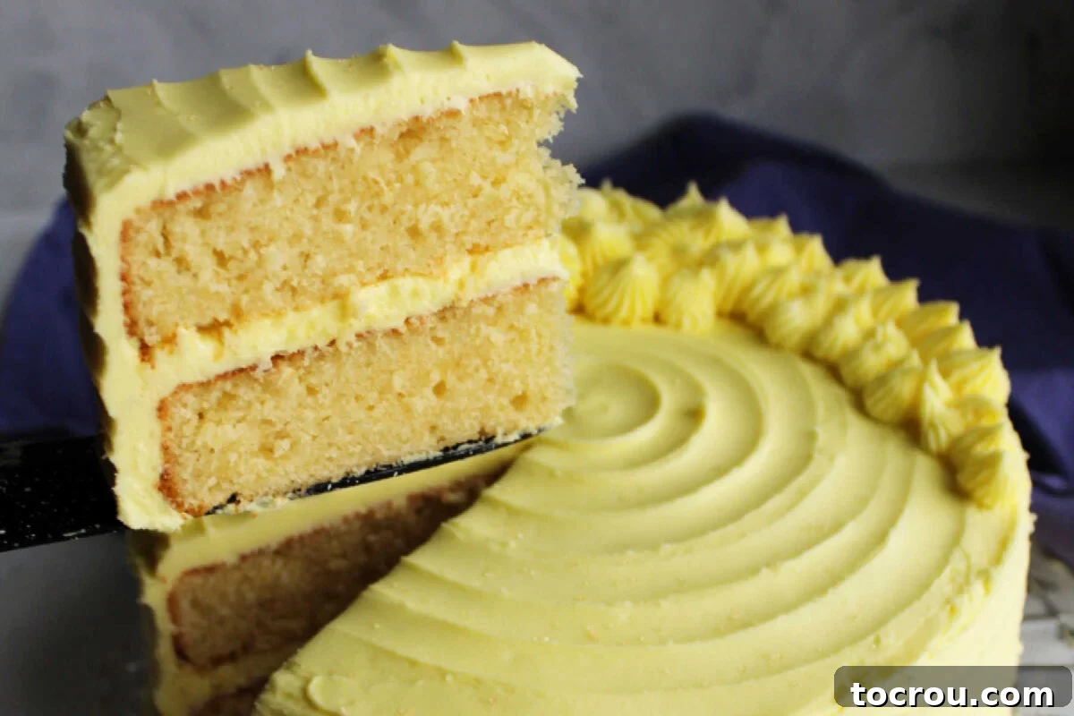 First slice of lemon velvet cake with lemon buttercream being lifted off serving platter. 