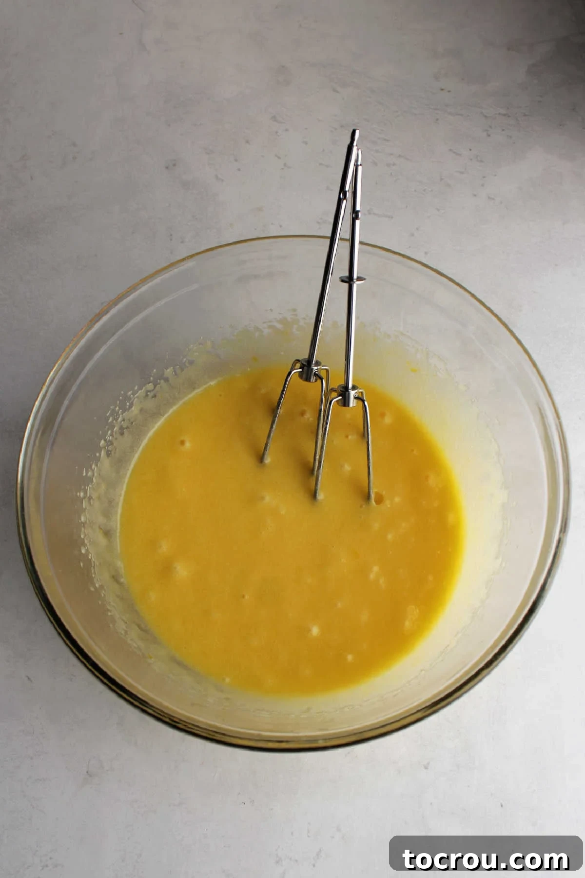 Mixing bowl with beaten eggs, oil, and sugar inside. 