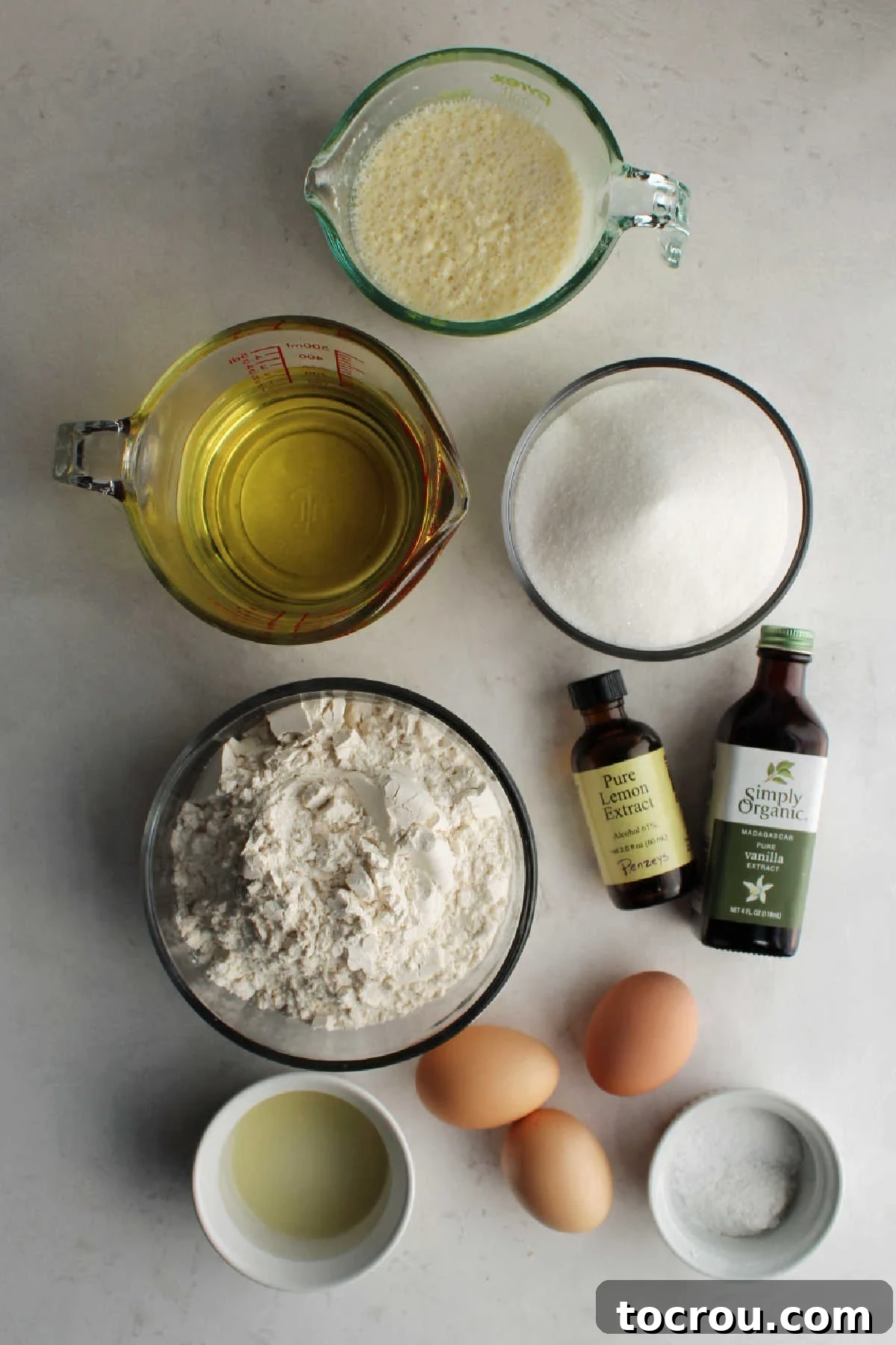 Ingredients including flour, salt, baking powder, buttermilk, oil, eggs, vanilla, lemon extract, and lemon juice ready to be made into lemon velvet cake. 