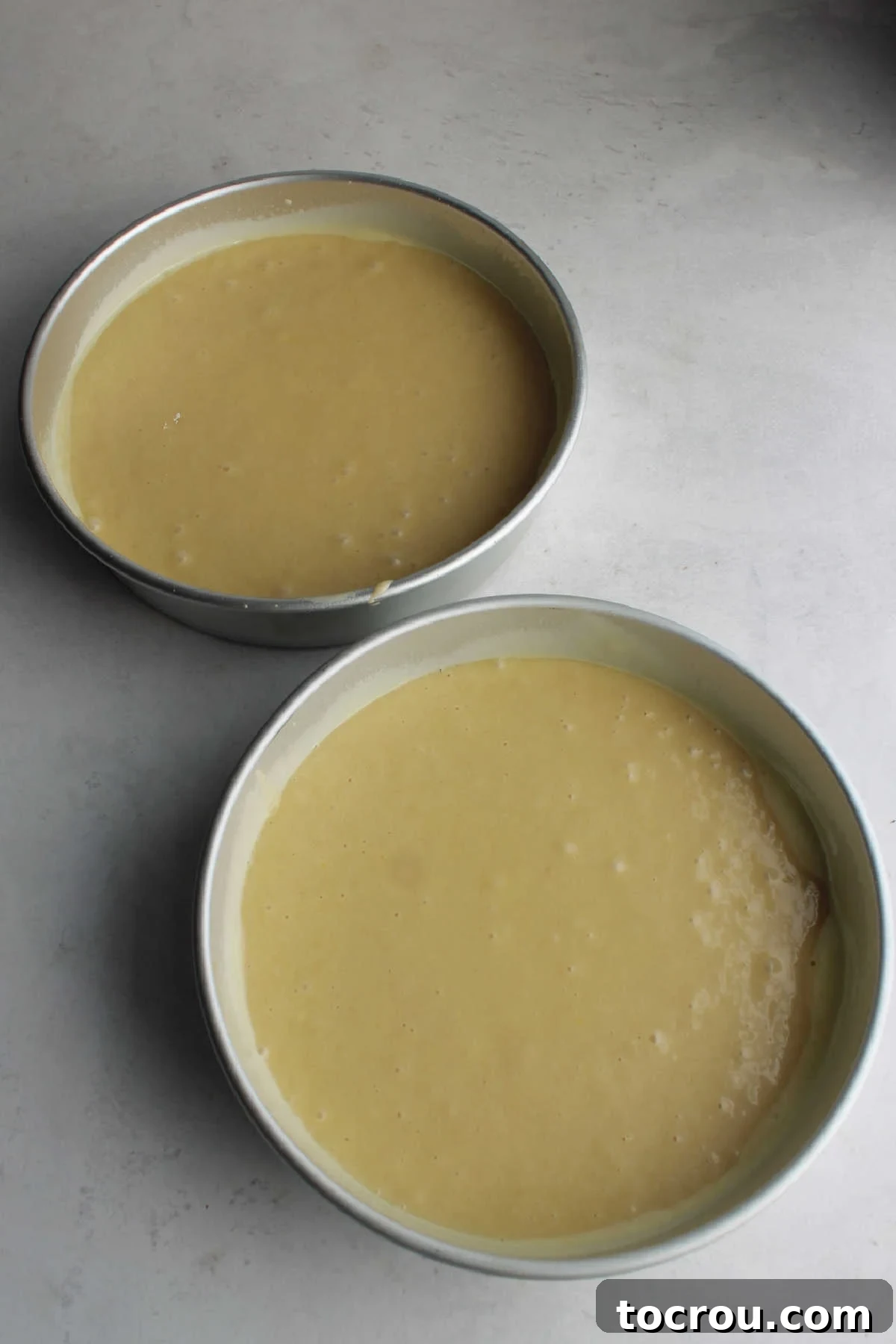 Pale yellow lemon velvet cake batter in two nine inch round cake pans. 