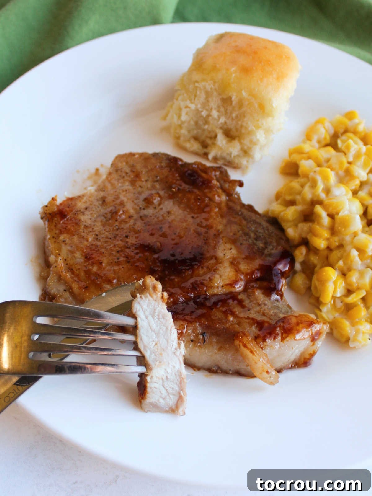 Inside a Tender Braised Pork Chop Fork holding a tender piece of braised pork chop, revealing the white, juicy interior contrasting with the dark, sticky, glazed exterior.