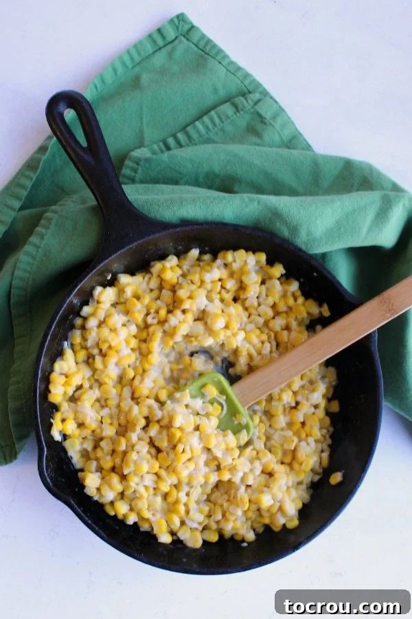 Creamy Skillet Corn: Freshly Prepared and Ready A cast iron skillet generously filled with a creamy corn mixture, accompanied by a spatula resting alongside, illustrating a ready-to-serve side dish.