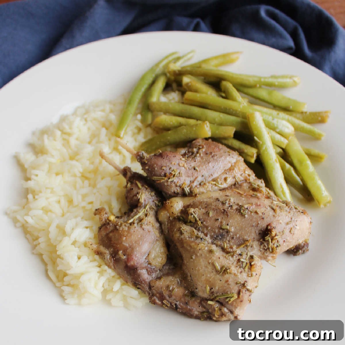 Lemon Rosemary Roasted Quail Dinner Spatchcocked lemon rosemary roasted quail served alongside perfectly roasted green beans and fluffy rice, presenting a complete and elegant meal.