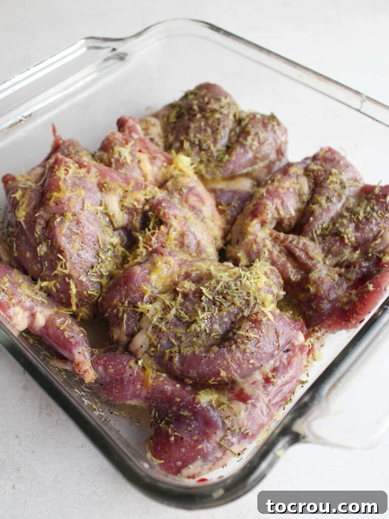 Marinating Quail A baking dish filled with raw, spatchcocked quail generously coated in the aromatic lemon and rosemary marinade, ready for refrigeration.