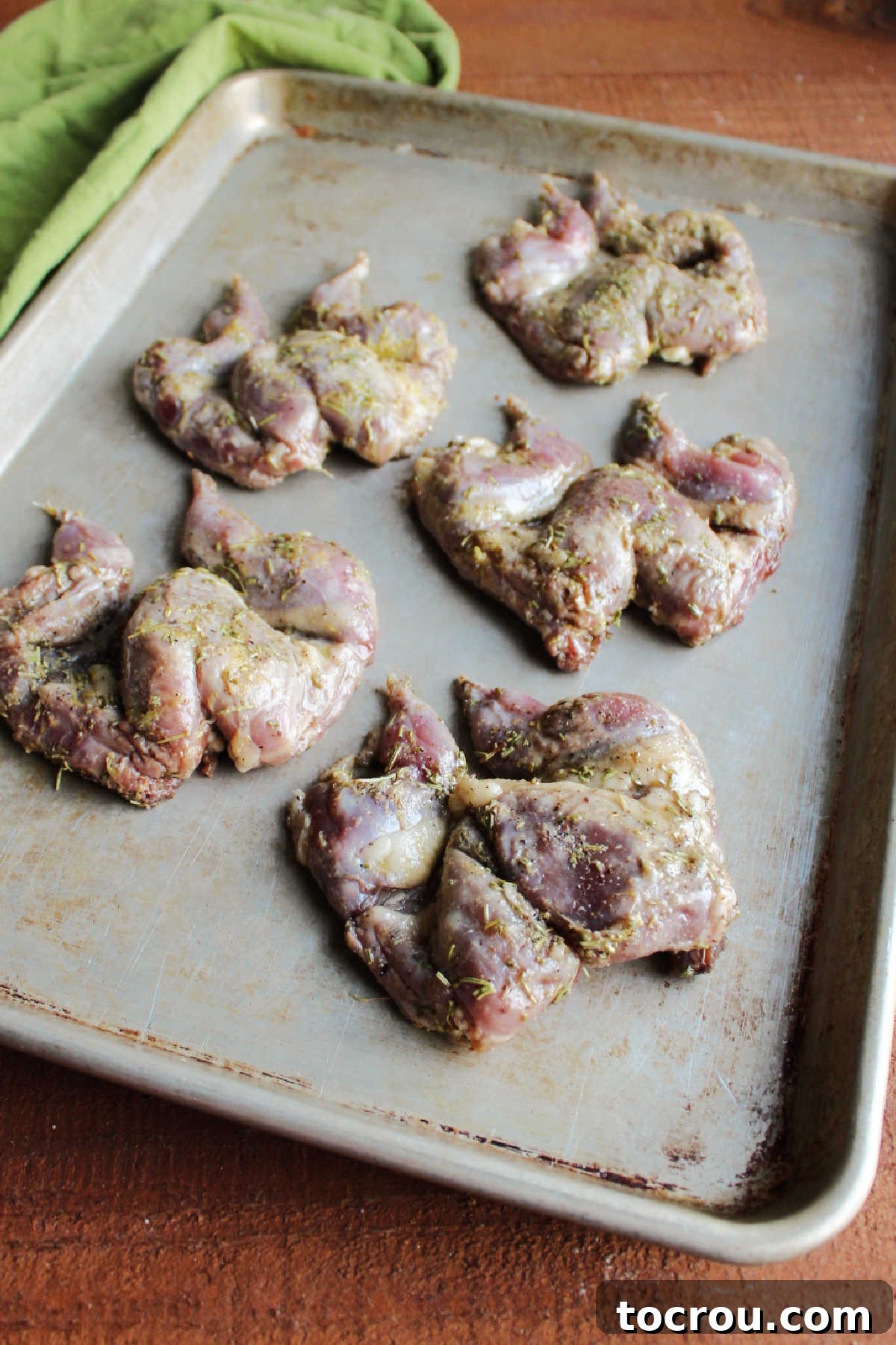 Quail on Sheet Pan Spatchcocked quail perfectly arranged and spread out on a sheet pan, ready for the oven with ample space for even roasting.