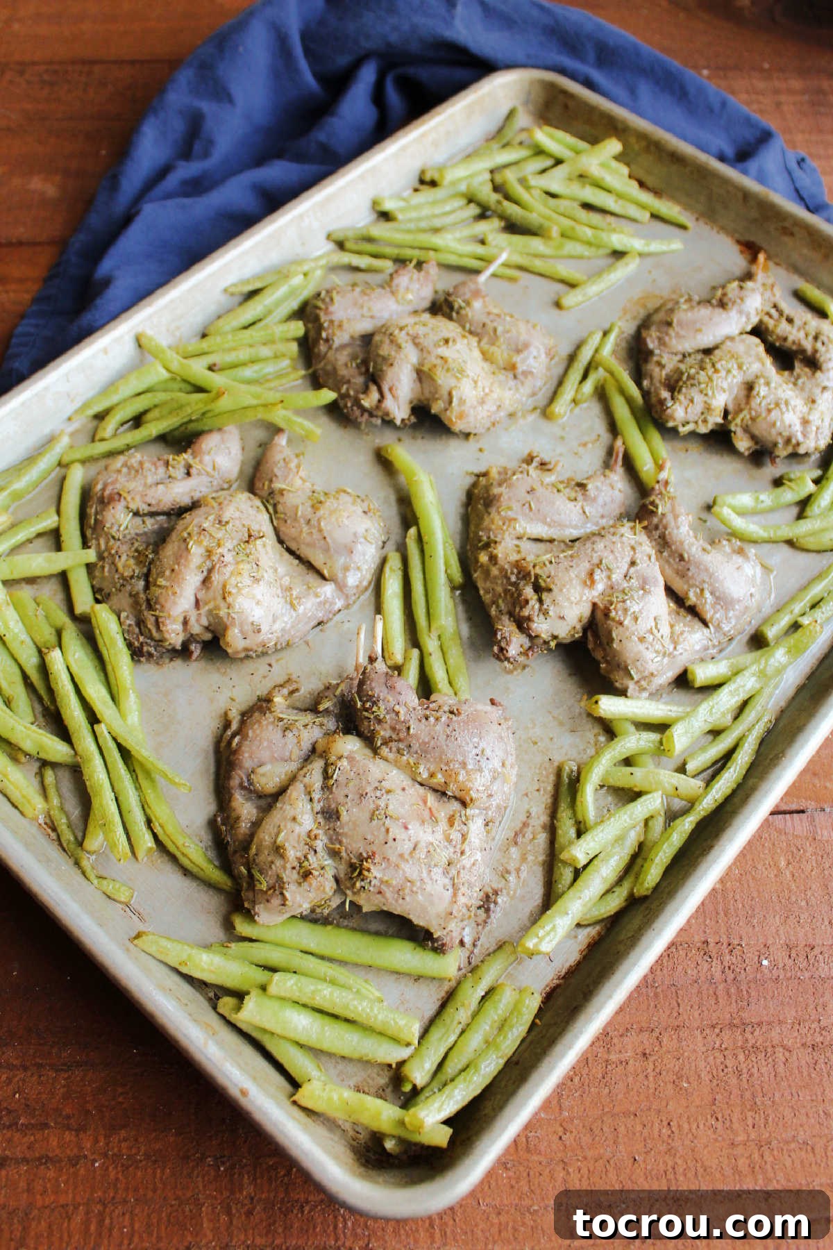 Roasted Quail and Green Beans A sheet pan showcasing beautifully roasted quail and vibrant green beans, golden brown and perfectly cooked, ready to be served.
