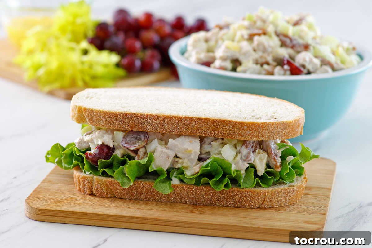 A perfectly assembled sandwich, featuring rich pineapple chicken salad with juicy grapes and fresh lettuce, inviting a delicious bite.
