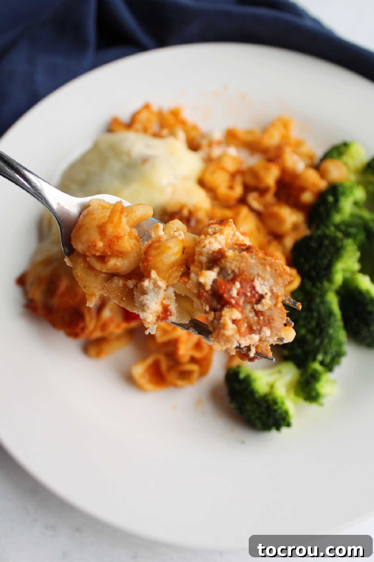 A delicious bite of cheesy pasta bake Bite of no boil baked pasta on fork with sausage and cheese, ready to eat.