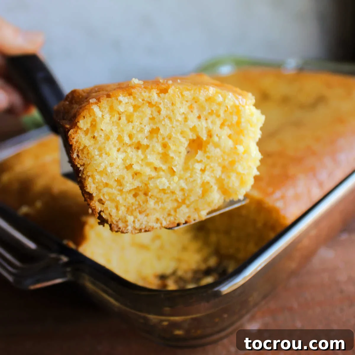 Easy Sweet Cake Mix Cornbread Spatula lifting a golden piece of sweet cake mix cornbread out of a baking pan, highlighting its fluffy texture.