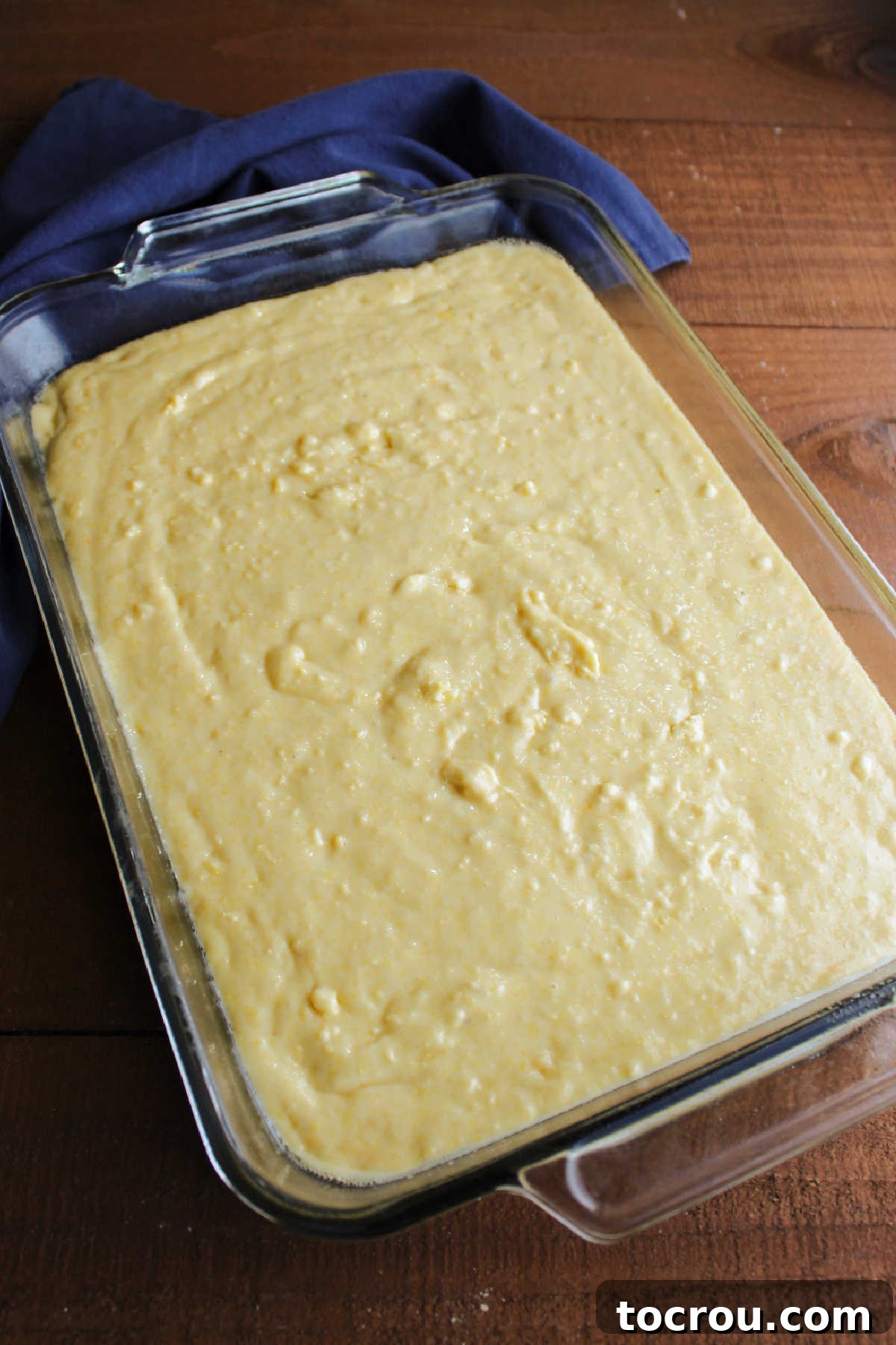 Cornbread Batter in Pan A 9x13-inch baking pan filled with smooth, golden cake mix cornbread batter, prepared and ready to bake.