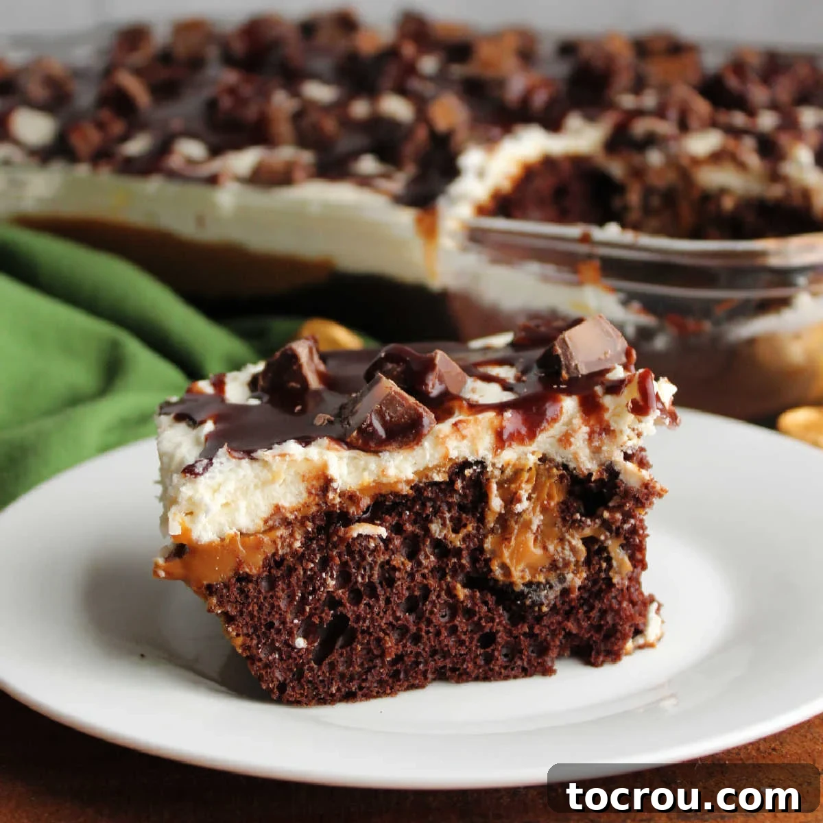 Rich Chocolate Comfort Cake with Velvety Frosting 5 A delightful piece of Rolo poke cake, featuring chocolate cake with luscious tunnels of dulce de leche, crowned with ermine frosting, candy bits, and a drizzle of fudge sauce.