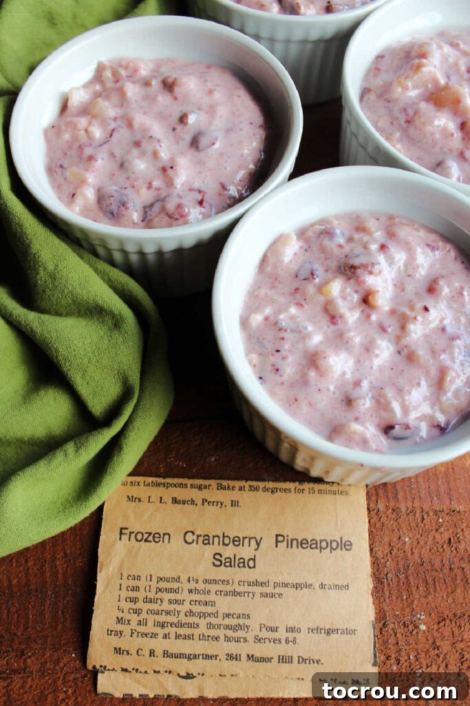 Ramekins filled with creamy cranberry pineapple salad mixture, alongside a yellowed newspaper clipping featuring the original recipe.