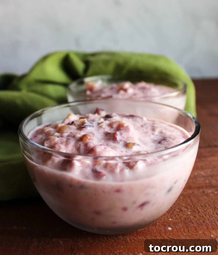 Side view of small glass bowls filled with frozen cranberry salad, showcasing its creamy texture and the delightful chunks of fruit and nuts within.