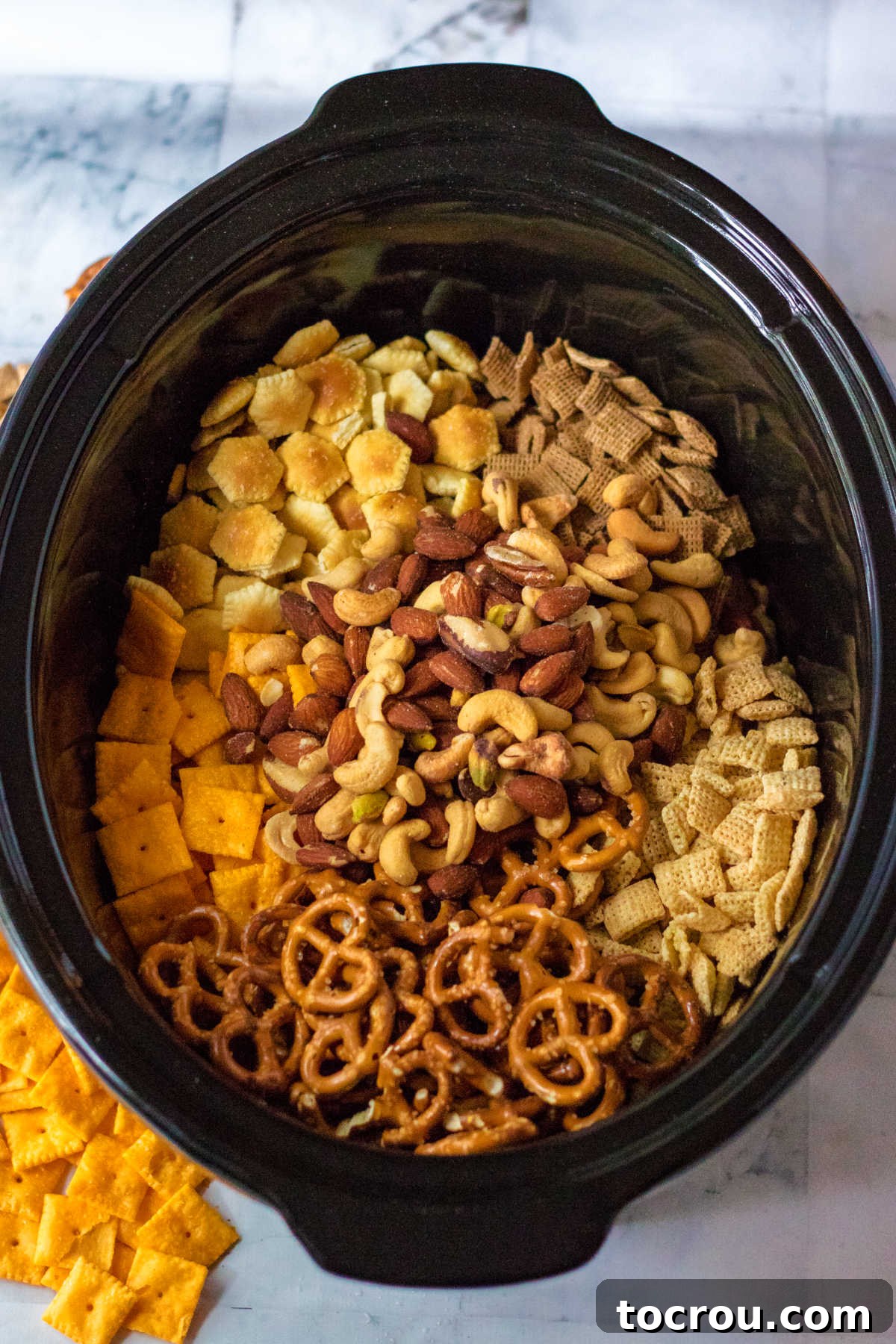 Slow cooker filled with crackers, cereal, nuts and more.