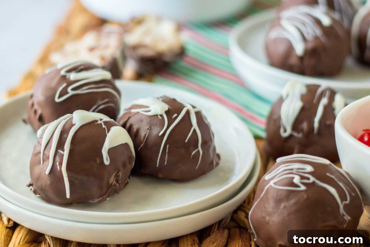 Homemade Martha Washington candies with creamy coconut, cherry, and pecan centers, coated in dark chocolate and elegantly drizzled with white chocolate.