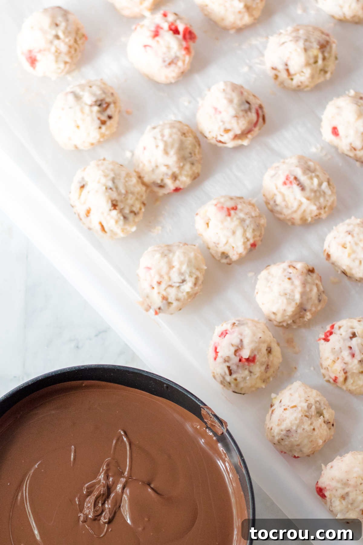 Portion-sized Martha Washington candy centers arranged on a baking sheet next to a bowl of perfectly melted chocolate, ready for dipping.