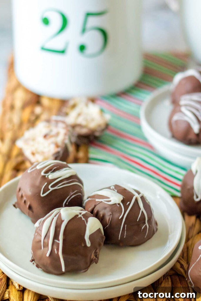 A plate showcasing Martha Washington candies coated in chocolate with white chocolate drizzle, and a nearby candy cut open to display its creamy coconut, pecan, and cherry filling.