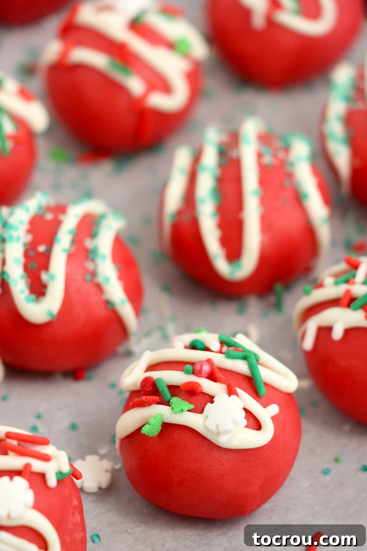 Tray of red velvet truffles drizzled with white chocolate and topped with sprinkles, arranged beautifully for a festive presentation.