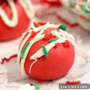Close up of smooth red velvet truffles topped with white chocolate drizzle and Christmas sprinkles.
