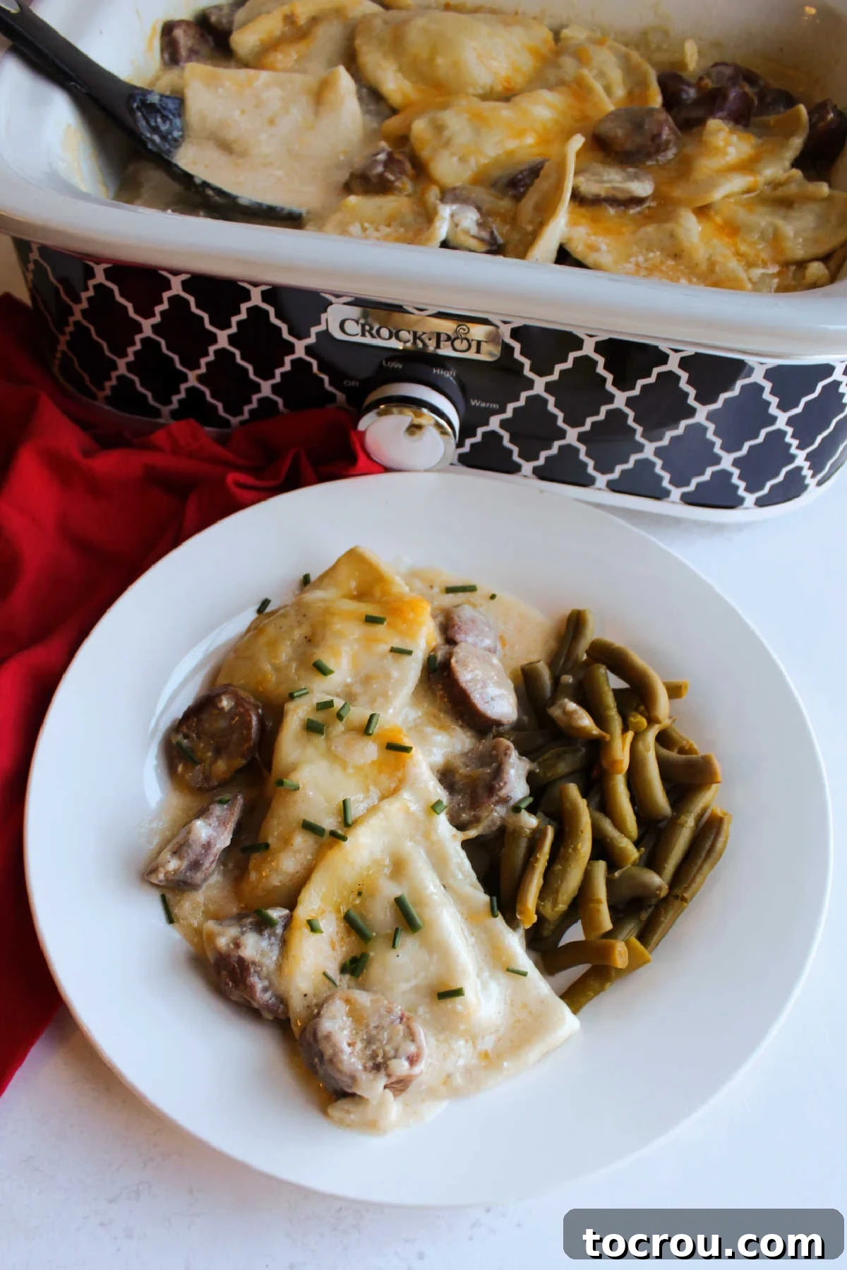 Cheesy sausage and pierogis casserole topped with chives, ready to eat.