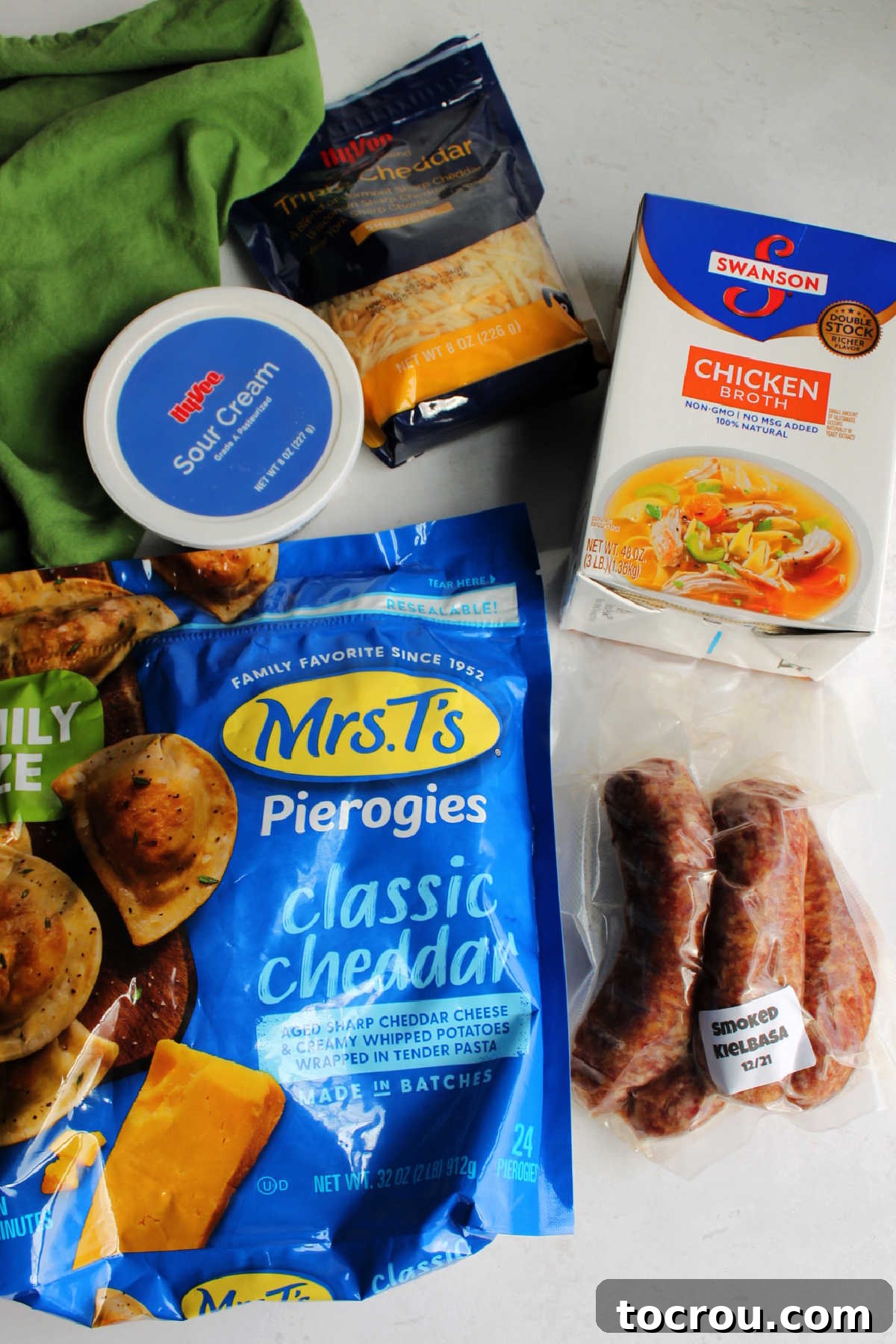 Ingredients: frozen pierogies, sour cream, shredded cheese, chicken broth and smoked sausage ready to be made into slow cooker casserole.