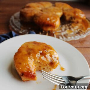 Fork next to a maple sticky bun with a gooey maple topping and soft cinnamon roll base.