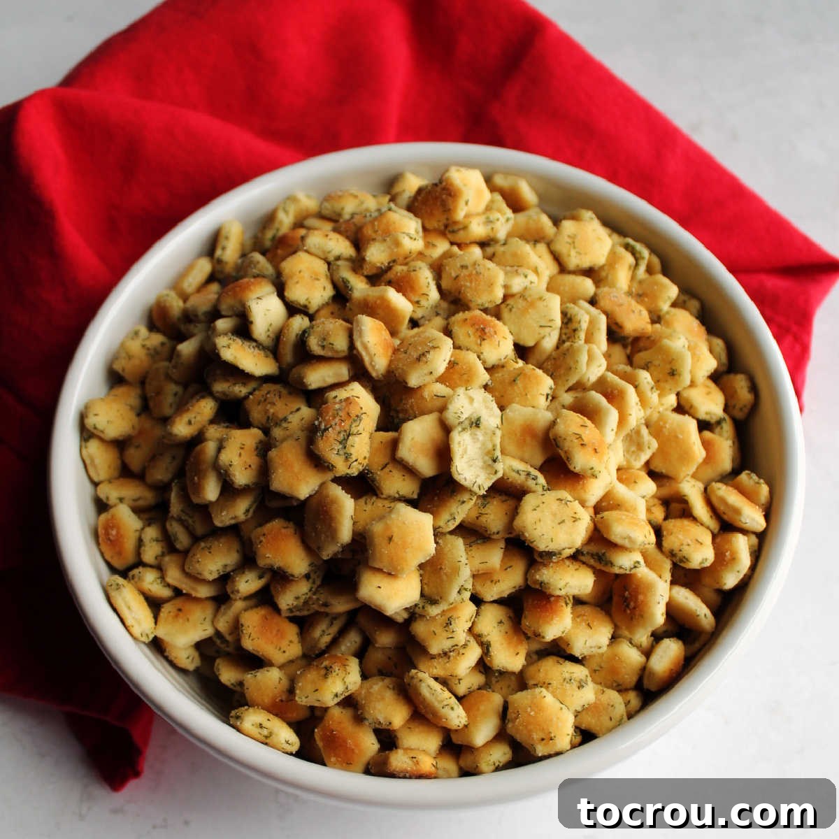 Bowl of soup crackers coated in ranch seasoning and dill, ready to eat.