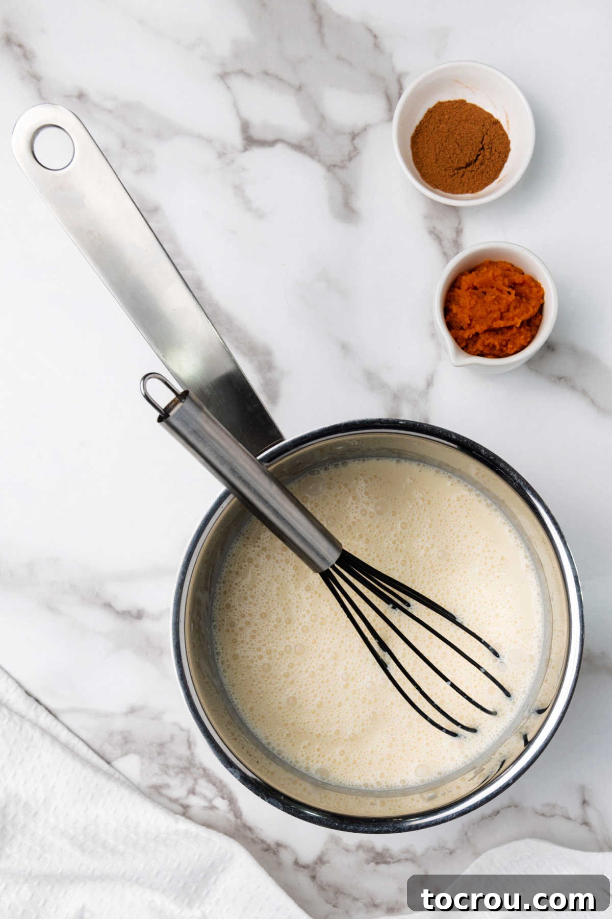 Close-up of pumpkin puree and pumpkin pie spice in separate bowls, ready to be combined into the coffee creamer mixture, emphasizing fresh ingredients.