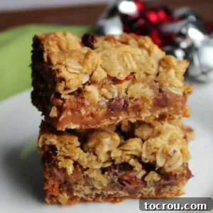 Stack of cookie bars with oatmeal crust and gooey caramel, chocolate and pecan centers.