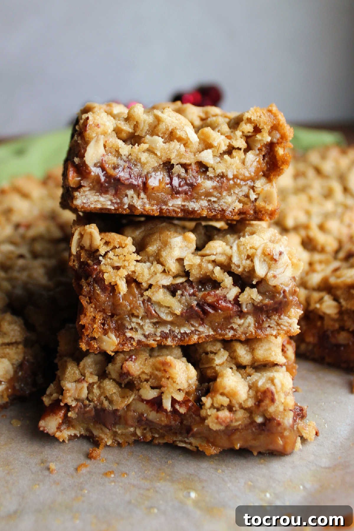 Perfectly cut Caramelitas squares stacked, showcasing the inviting oat crust and the luscious, gooey caramel, chocolate, and pecan filling within.