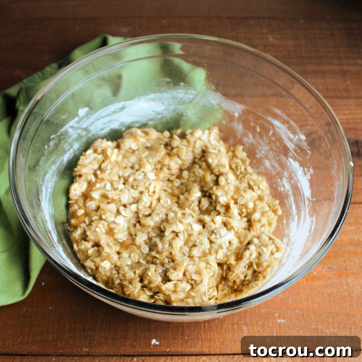 A mixing bowl filled with the dry ingredients for the oatmeal crust, including rolled oats, brown sugar, and flour, well combined.