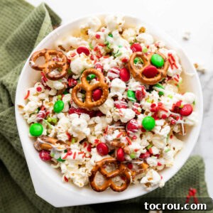Bowl of Christmas popcorn mix with pretzels, M&Ms, white chocolate and sprinkles. This delightful sweet and salty treat is perfect for holiday gatherings.