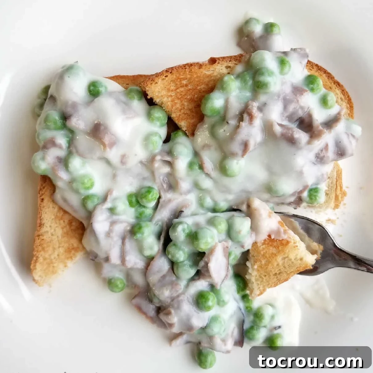 Creamed chipped beef with peas served over golden toast, a classic and comforting dish.