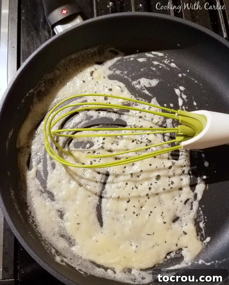 Skillet with a melted butter and flour roux and whisk, ready to make cream sauce.