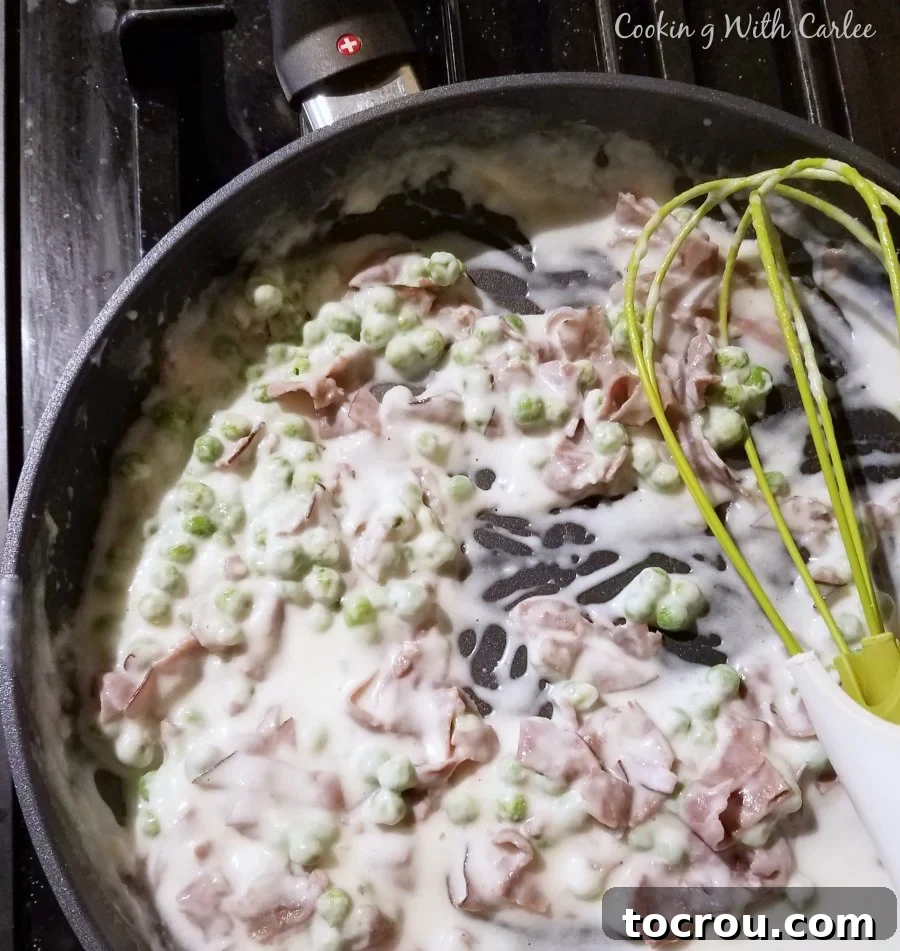Beef in milk gravy with peas in skillet ready to be served over toast.