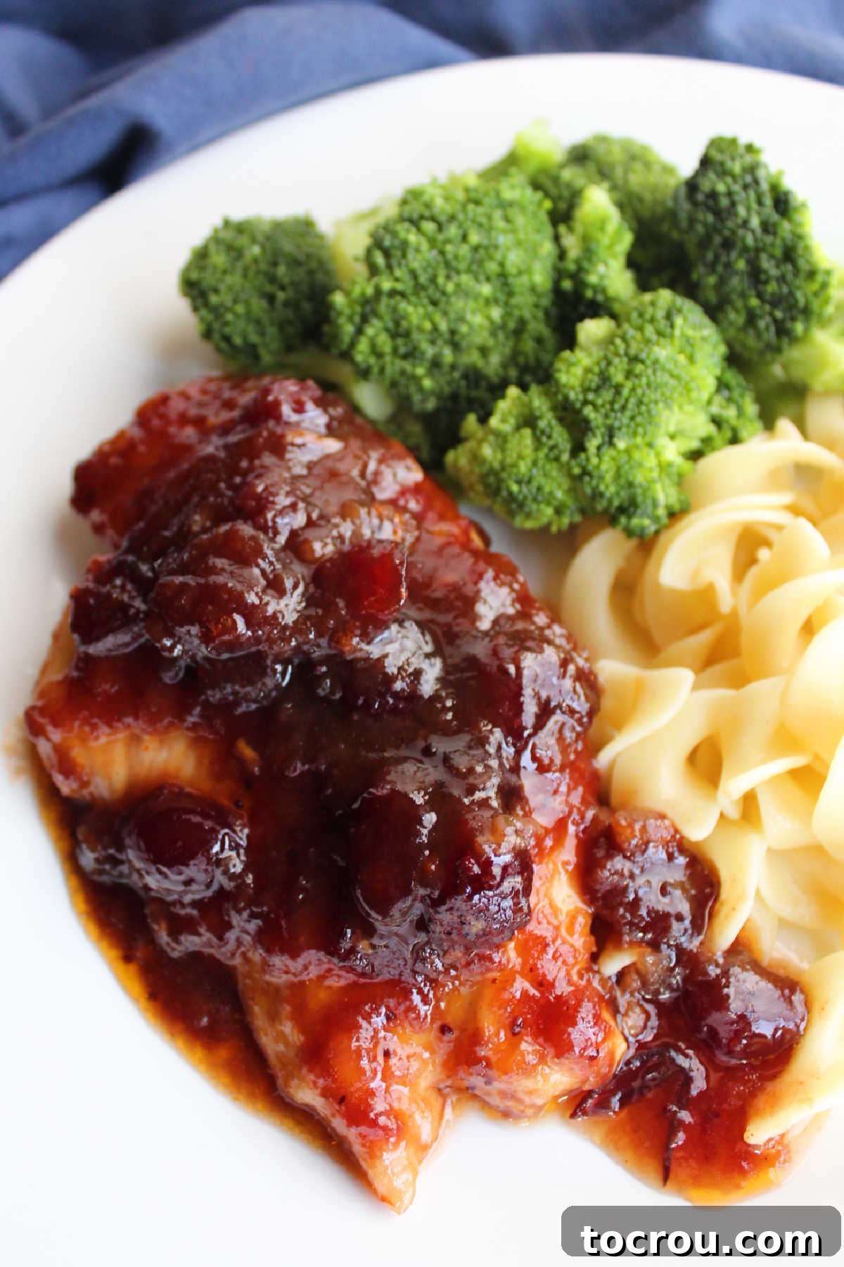 Cranberry chicken breast served with egg noodles and steamed broccoli.