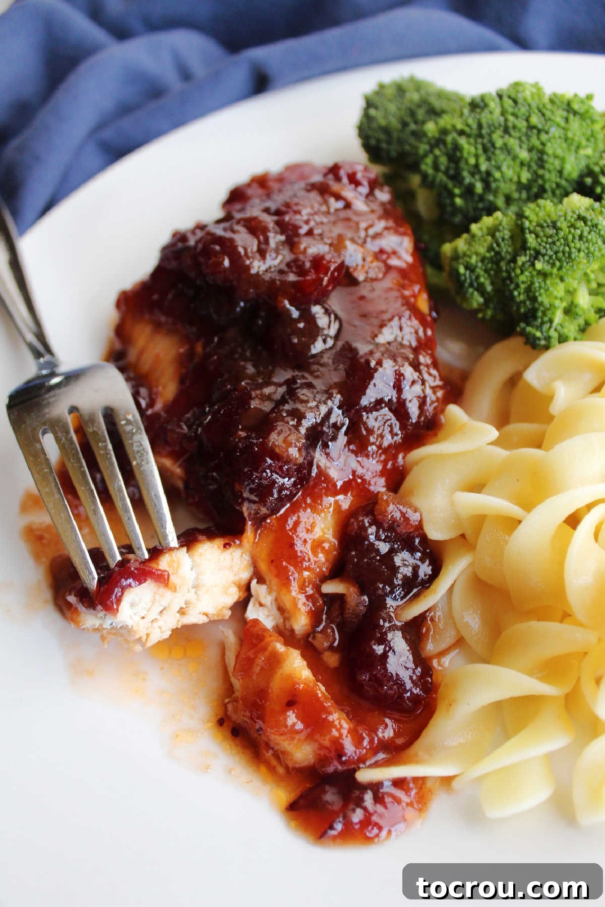 Bite of cranberry chicken on fork ready to eat.