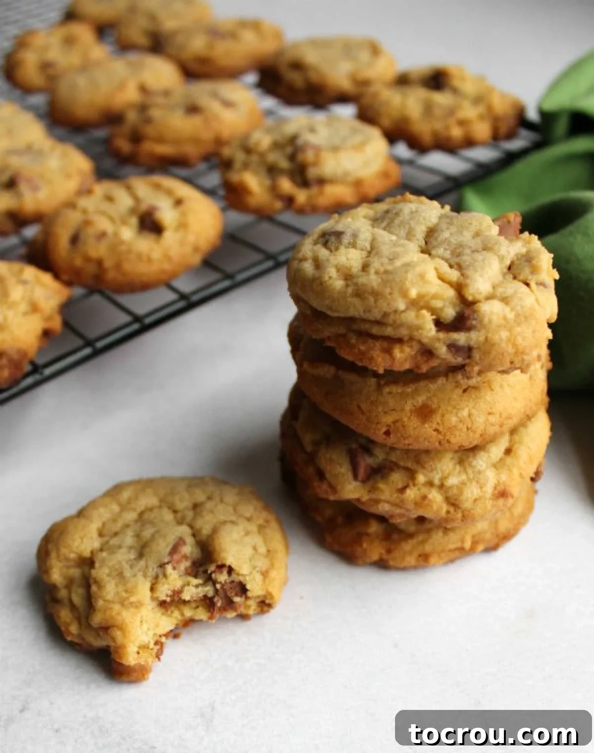 Taste of Home chocolate chip cookies with pudding mix in the dough on cooling rack, one with a bite taken out showing the soft texture inside.