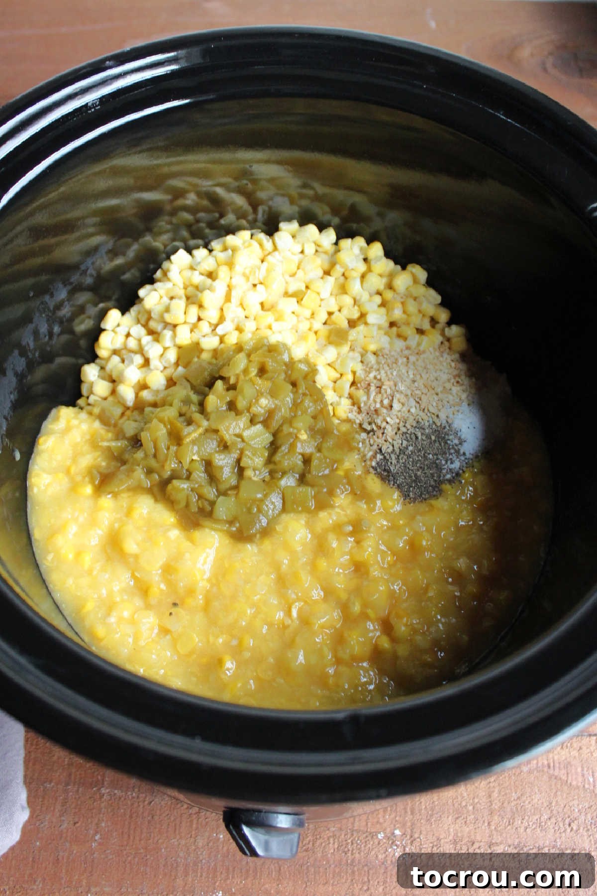 Frozen corn, creamed corn, chopped green chilies and seasonings in crockpot.