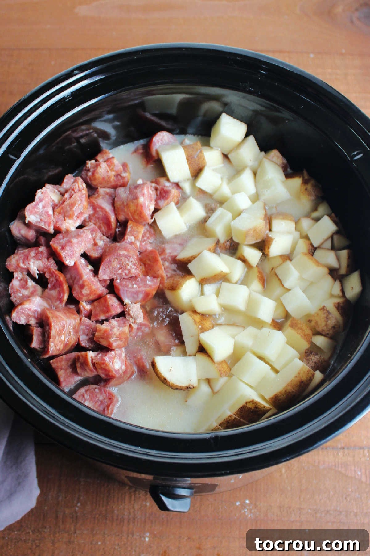 Smoked sausage, diced potatoes, stock and evaporated milk added to crockpot ready to cook.